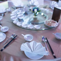 Dinner table Chinese style. The round table set in restaurant with bowl spoon chopsticks on the table in natural light in a day time to present the luxury setting in high class Chinese restaurant.